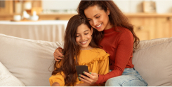 mãe e filha sentadas no sófa mexendo no celular