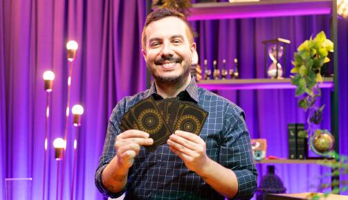 André Mantovanni sorrindo segurando cartas de tarô