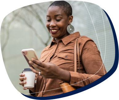 Acesse calendário, mensagens e contatos em um só lugar mulher negra de blusa de frio mexendo no celular com um café na mão