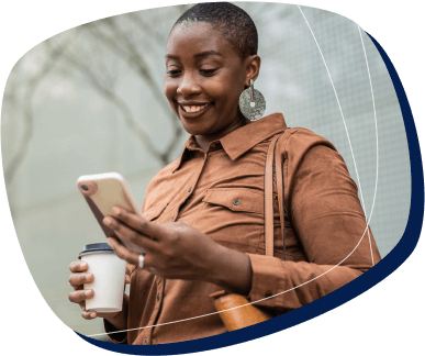 Acesse calendário, mensagens e contatos em um só lugar mulher negra de blusa de frio mexendo no celular com um café na mão