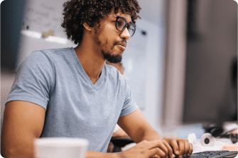 homem usando óculos e barba mexendo no computador