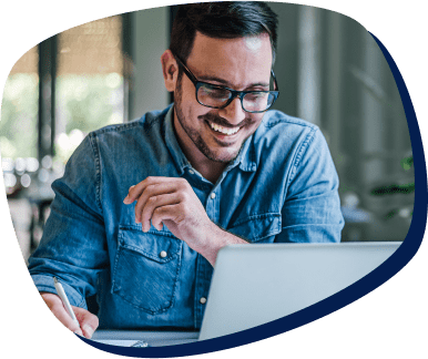 homem usando óculos e camisa jeans sorrindo e mexendo no computador