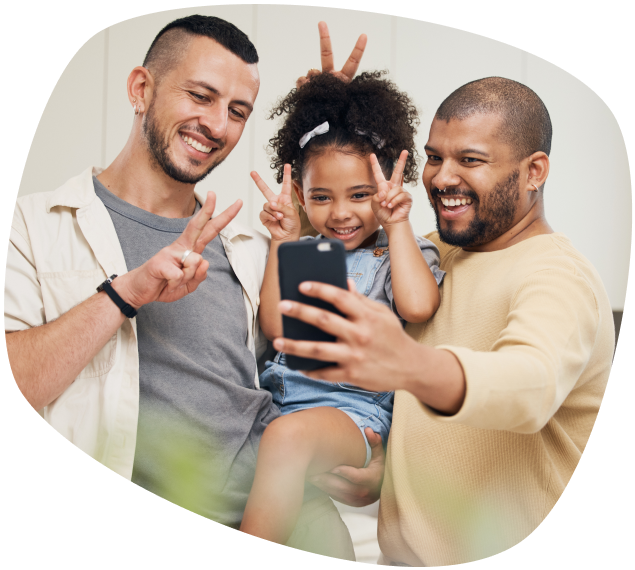 dois homens segurando uma criança no colo fazendo dois com as mãos