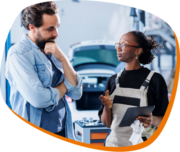 homem e mulher conversando  em uma oficina. mulher veste um macacão