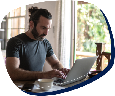 Homem de barba e camiseta mexendo no computador